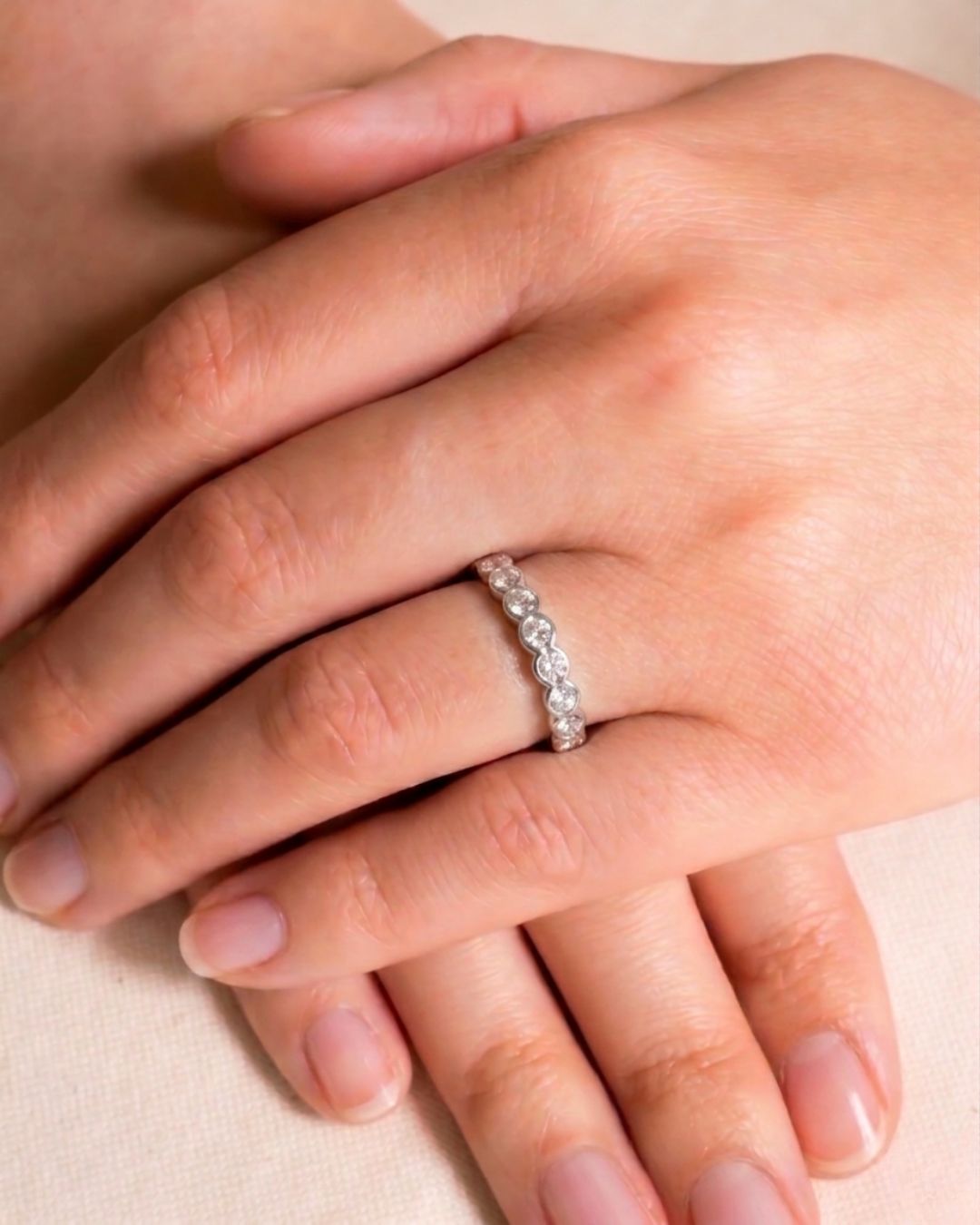Silver ring with dainty scalloped edge diamonds on a hand.