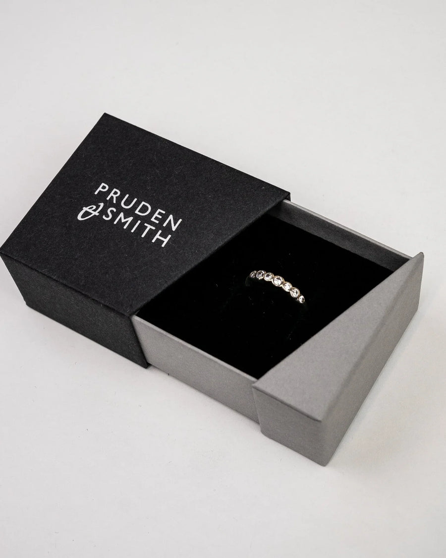 Silver ring with diamonds in a black and gray box.