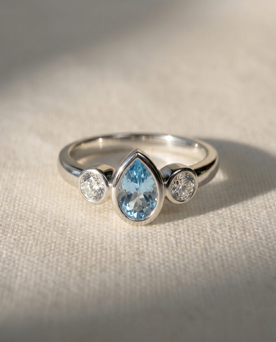 Platinum ring with a pear-shaped aquamarine and two round diamonds.