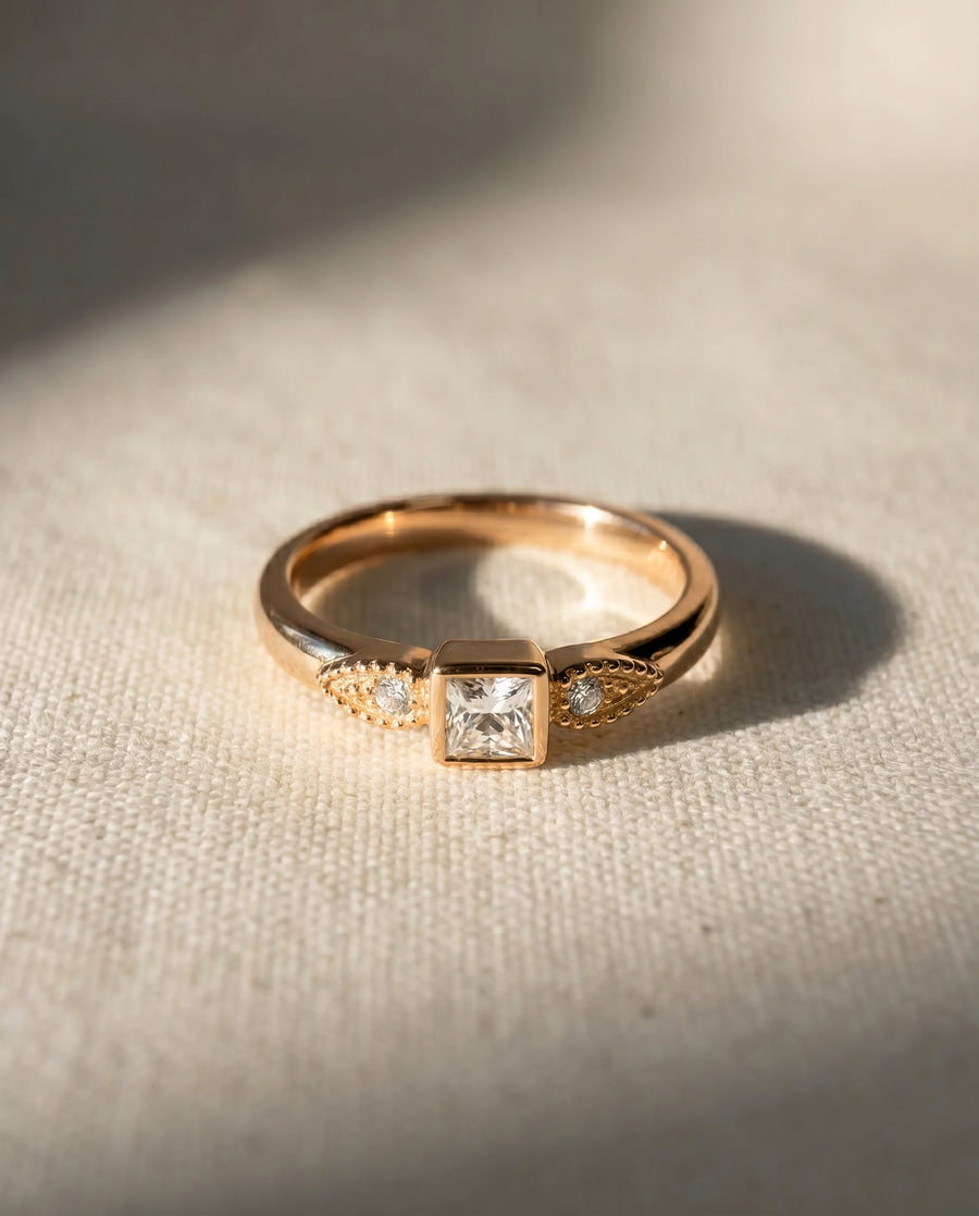 18ct rose gold ring with a princess-cut diamond and two round side diamonds.