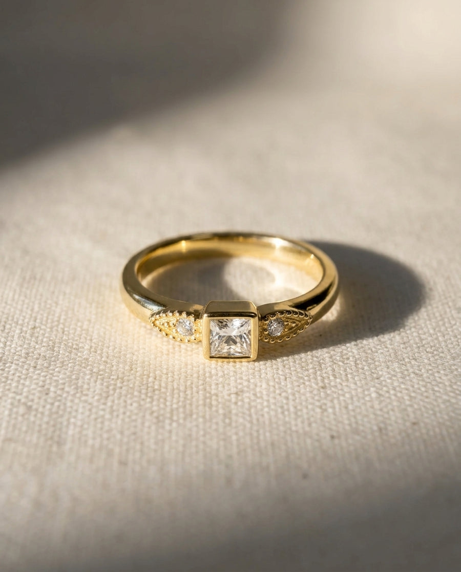 18ct yellow gold engagement ring with a princess-cut diamond and two small round diamonds.