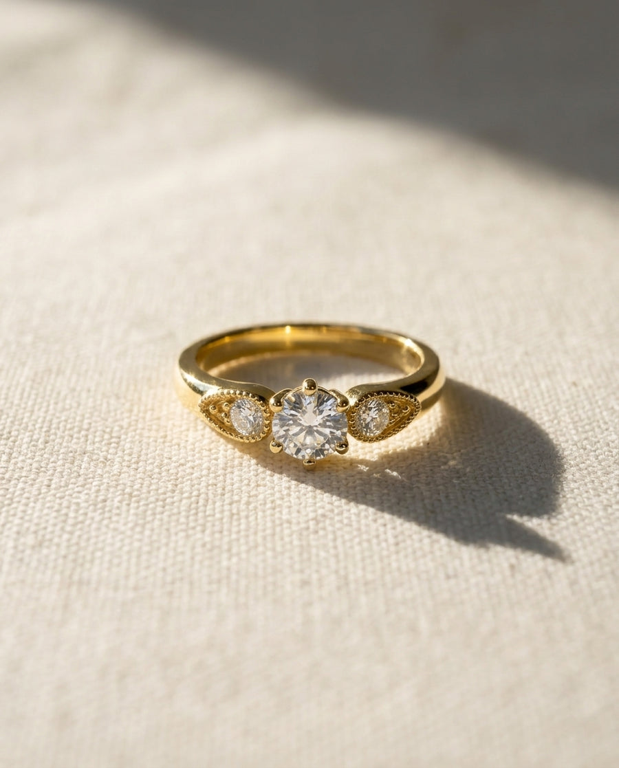 18ct yellow gold engagement ring with a round diamond and two smaller side diamonds.