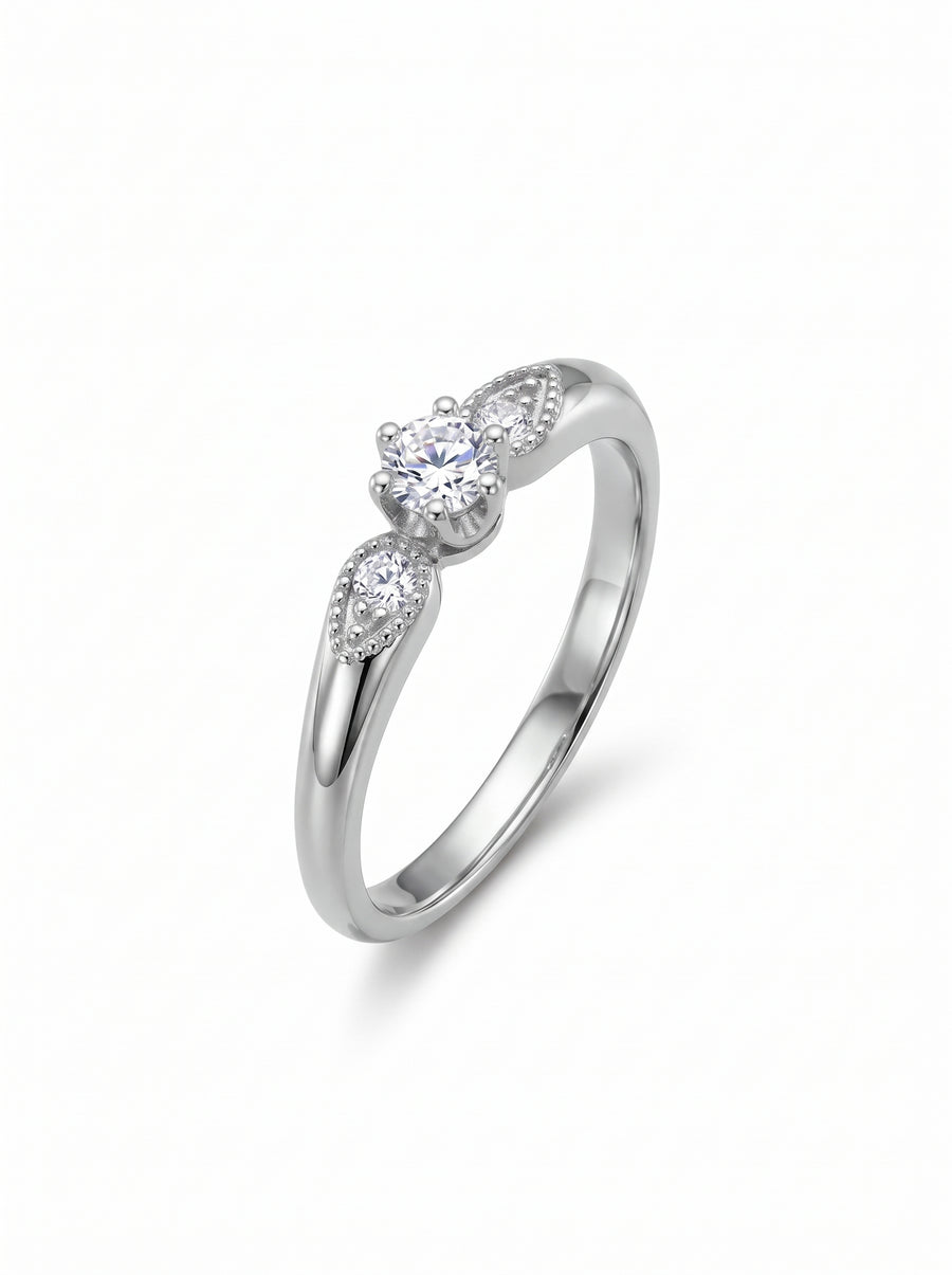 Silver engagement ring with a round center diamond and two smaller marquise-shaped side stones on a vintage band.