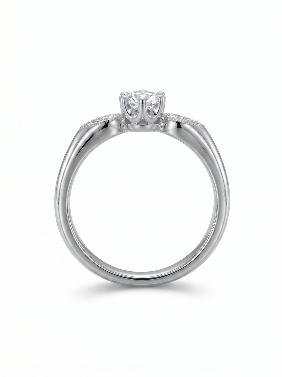 Silver engagement ring with a round center diamond and small accent stones on the shoulders.
