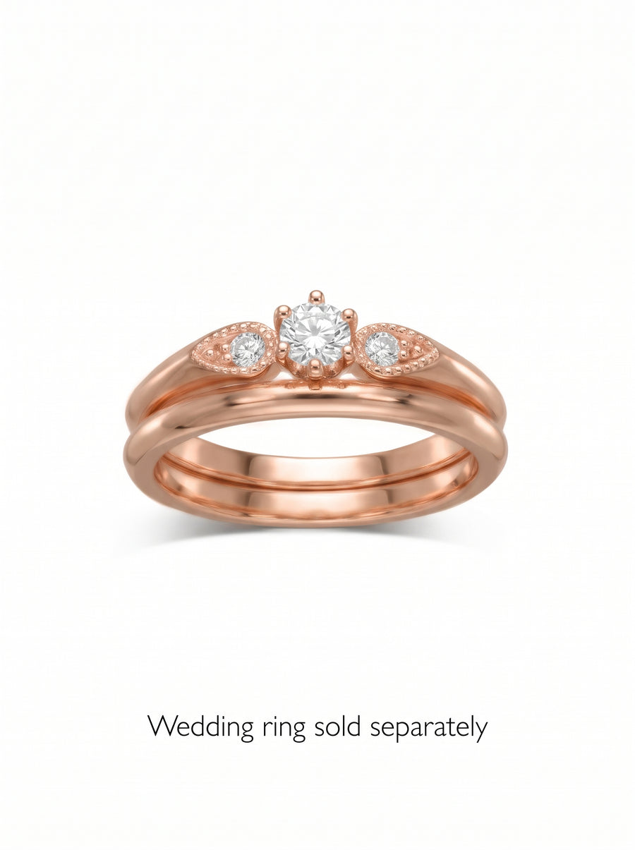 Rose gold engagement ring with a round center diamond and two marquise-shaped side stones on a vintage band.