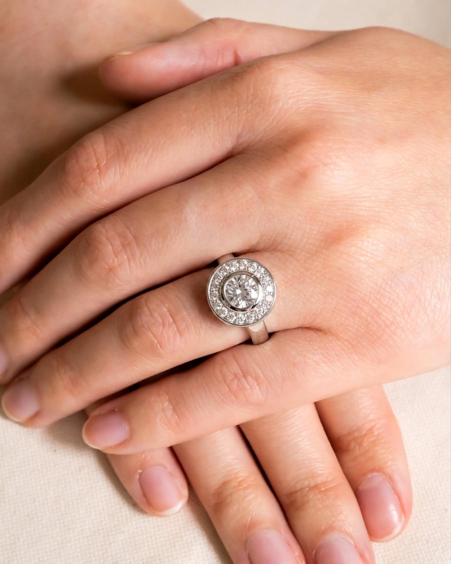 Silver diamond cluster engagement ring on a hand.