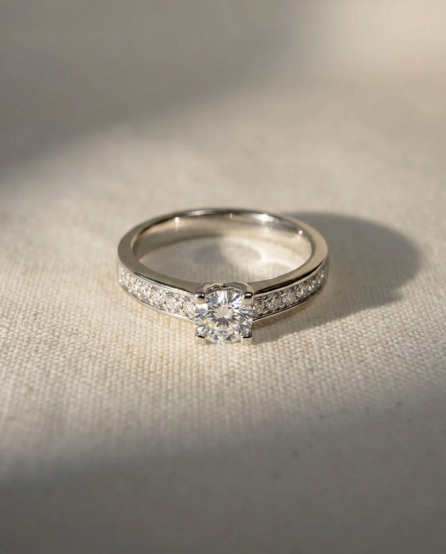Silver diamond shoulder engagement ring with a round center diamond.