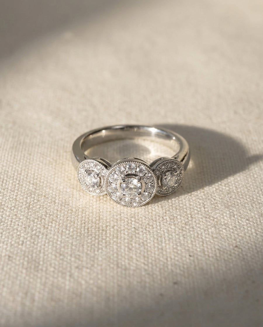 Platinum trilogy cluster engagement ring with three round diamonds.