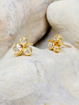 Three diamond and gold earstuds with stone background