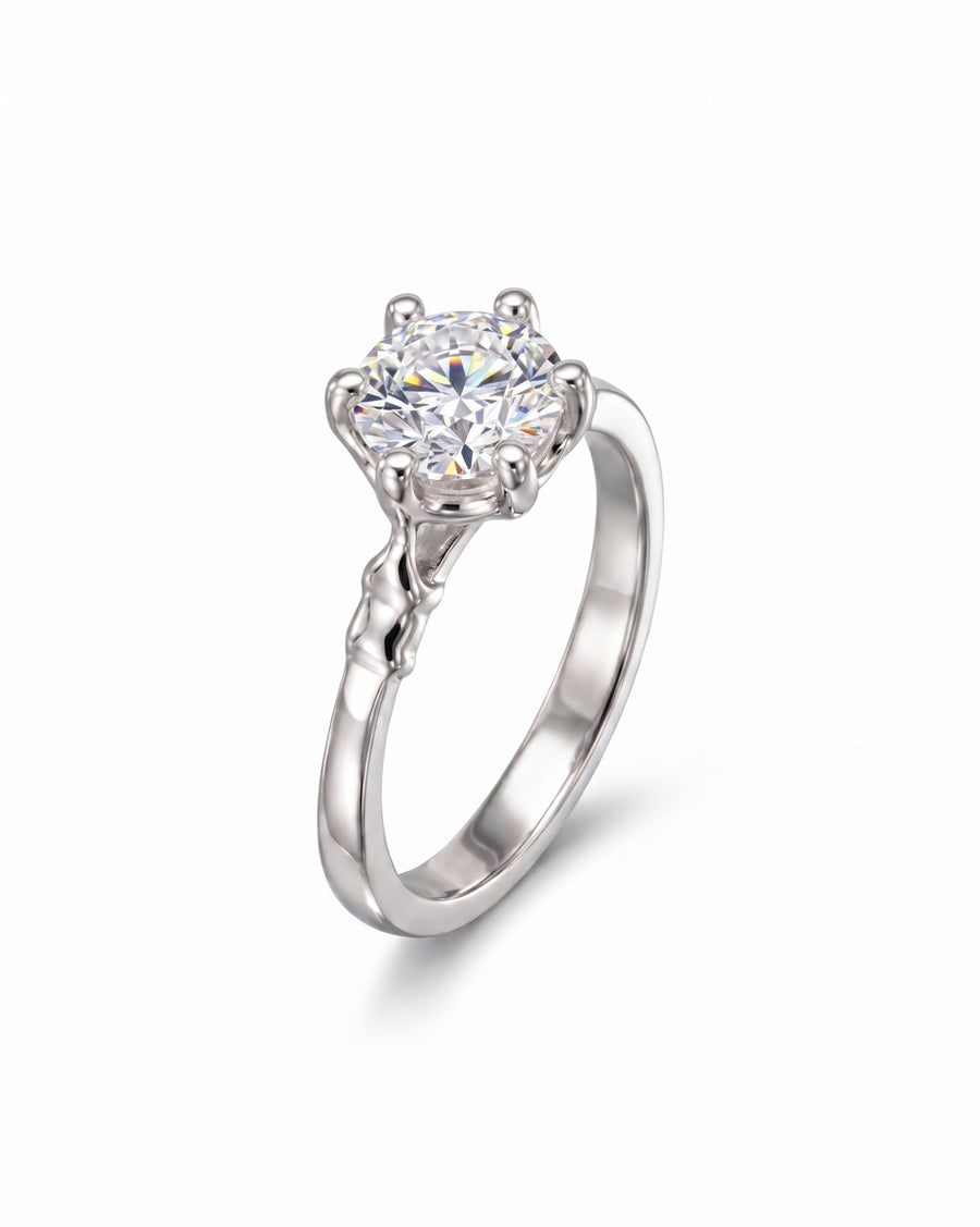 Silver engagement ring with a large round diamond and elephant motif prongs.