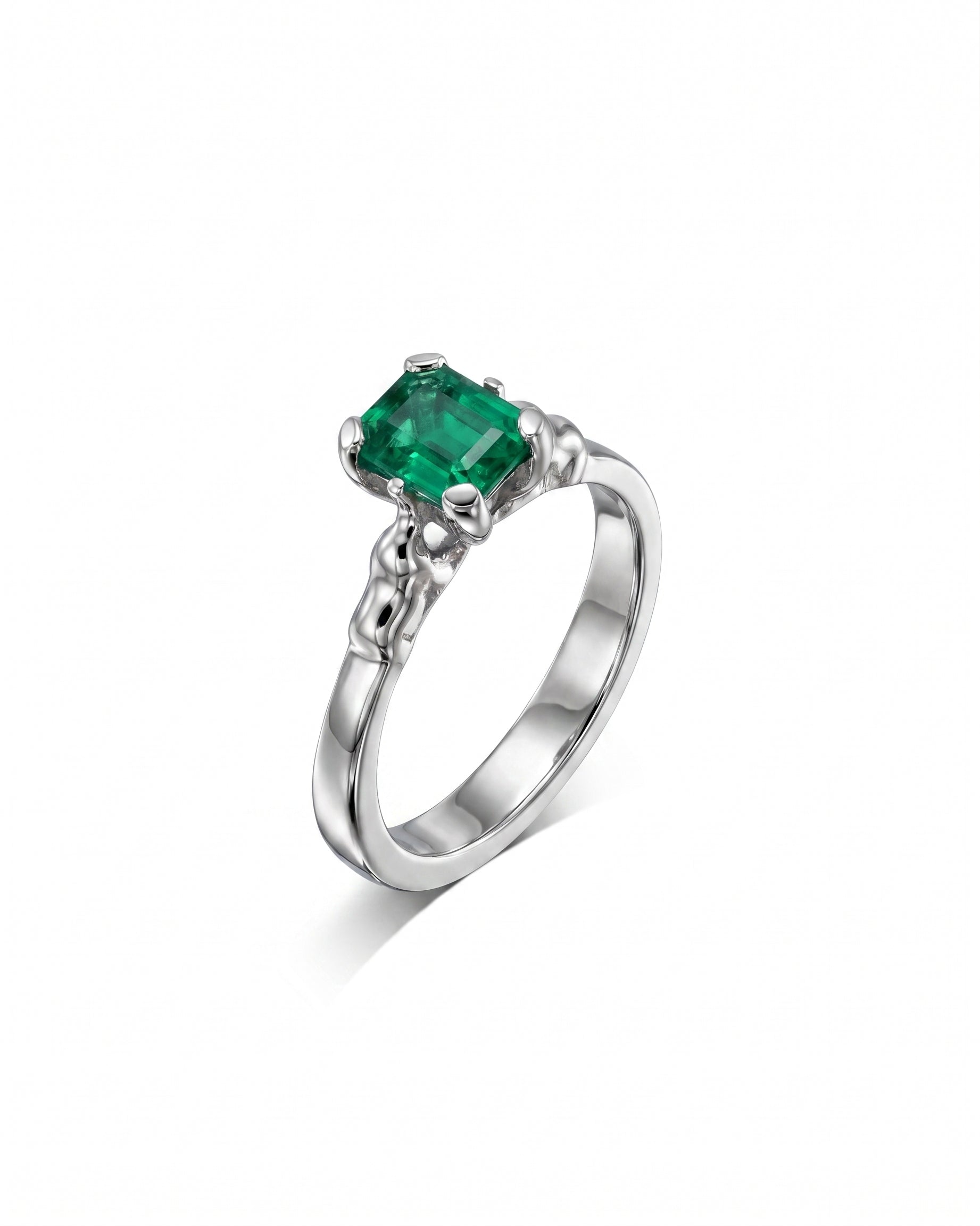 Silver ring with an emerald-cut green emerald and elephant motif details.