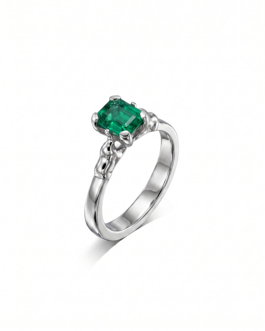 Silver ring with an emerald-cut green emerald and elephant motif details.