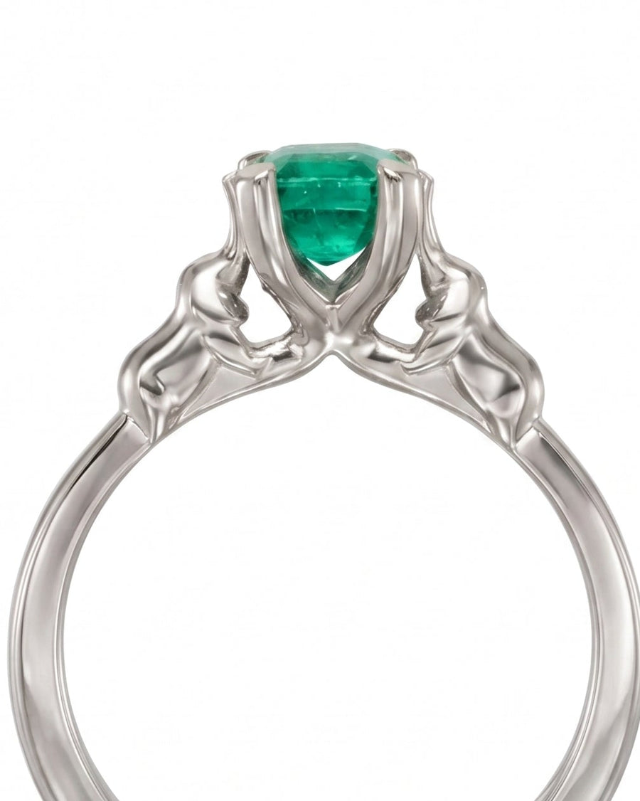 Silver ring with an emerald gemstone and elephant motif details on the band.