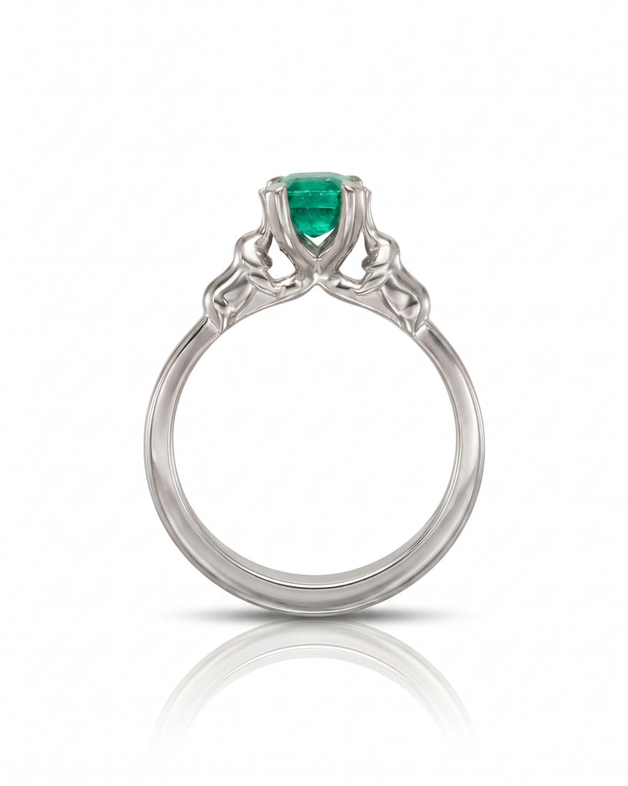White gold engagement ring with a round emerald and elephant motif.
