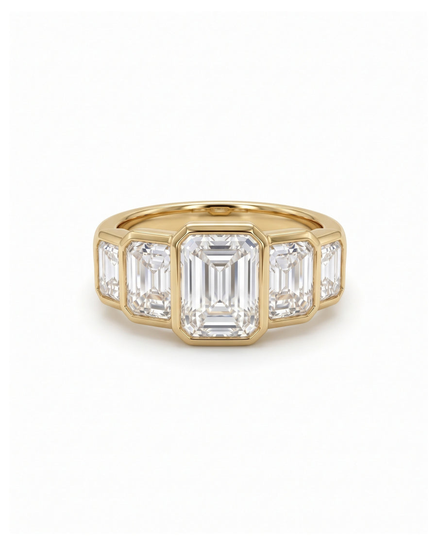 Gold ring featuring five bezel-set emerald cut diamonds in a horizontal art deco arrangement.
