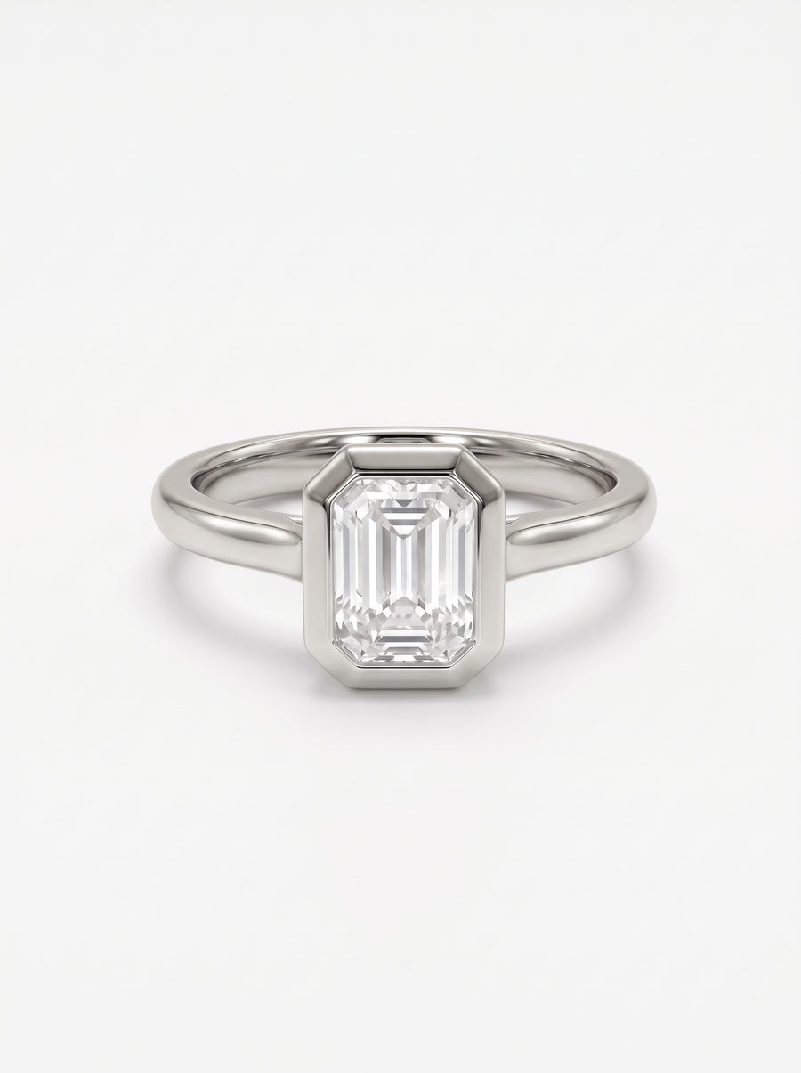 Emerald cut diamond engagement ring in a platinum bezel setting with a cathedral band.
