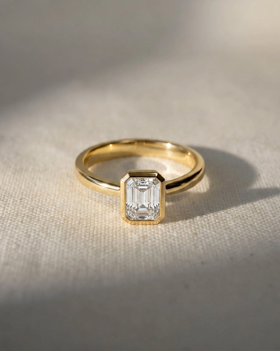18ct yellow gold engagement ring with a 1ct lab-grown emerald cut diamond in a bezel setting.