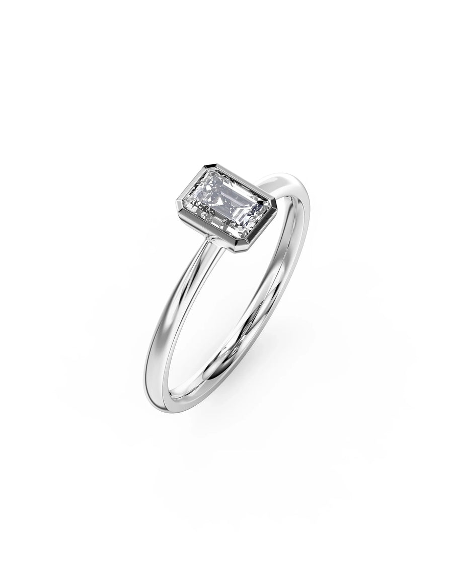 Silver ring with an emerald cut diamond in a bezel setting.