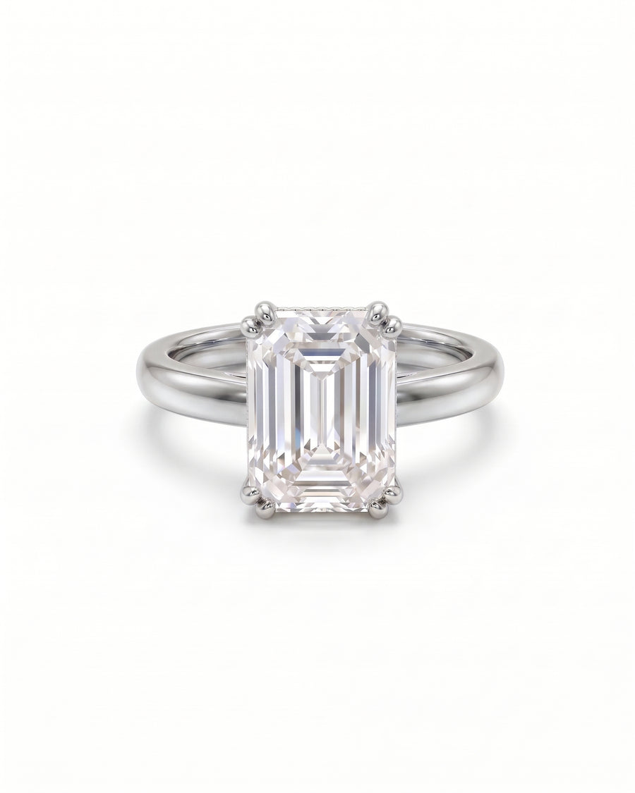 Emerald-cut solitaire engagement ring in polished platinum with a four-prong cathedral setting.
