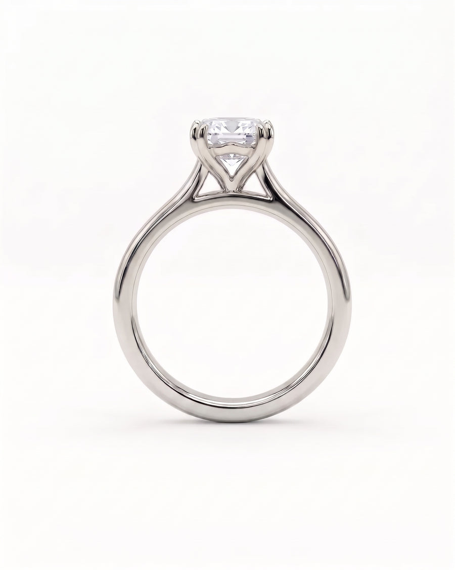 Emerald-cut diamond solitaire engagement ring in a polished silver-tone metal cathedral setting.