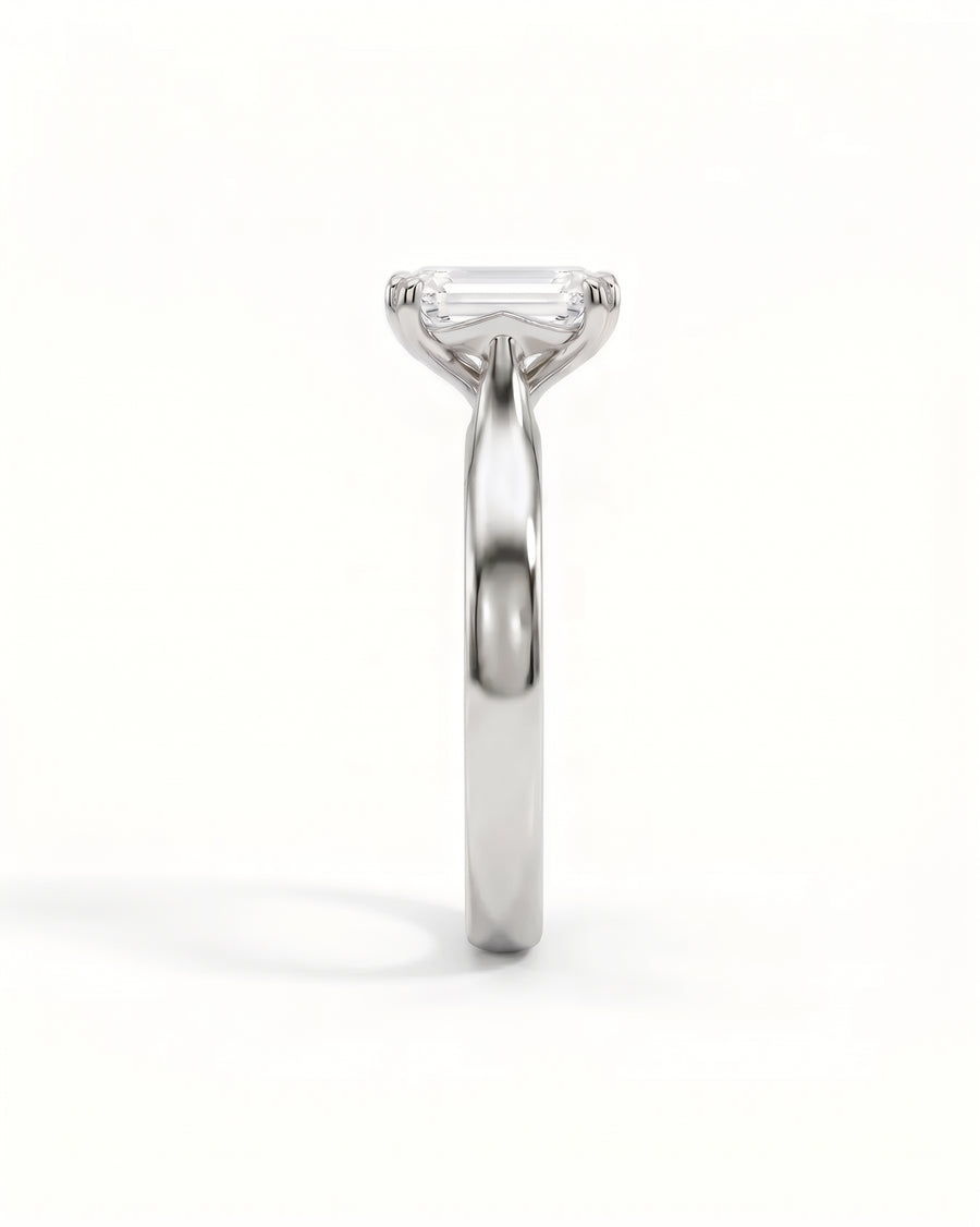 Emerald-cut diamond solitaire engagement ring in polished white gold with a cathedral setting.