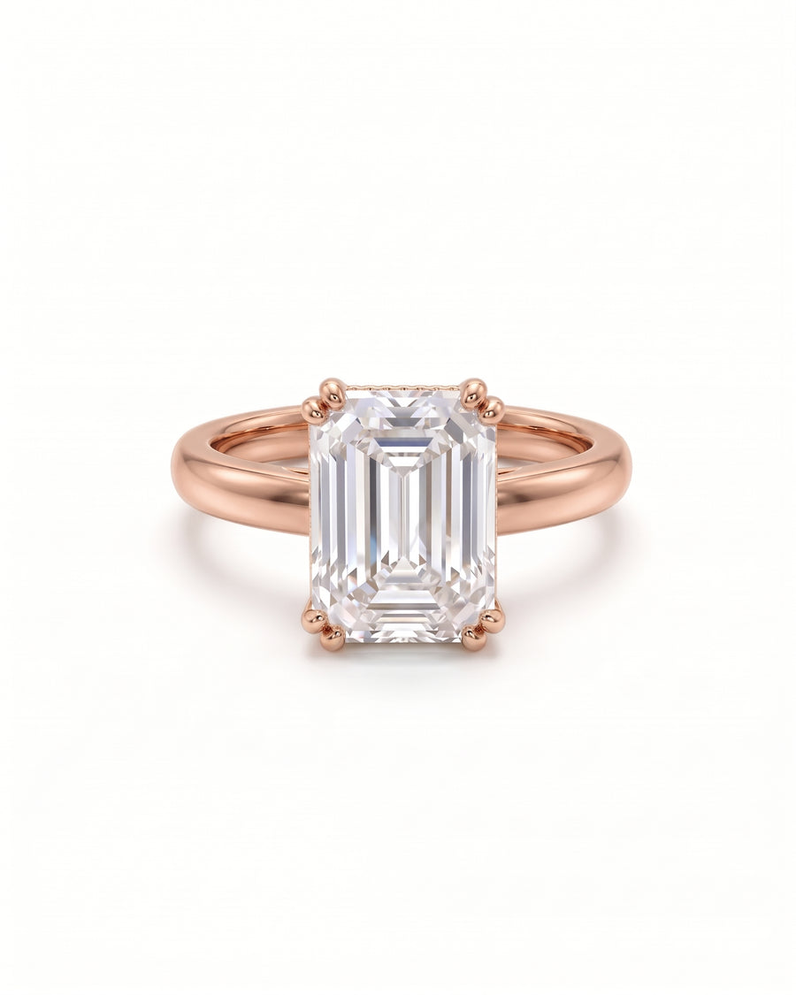 Emerald-cut solitaire engagement ring in 18ct rose gold with a cathedral setting on a white background.