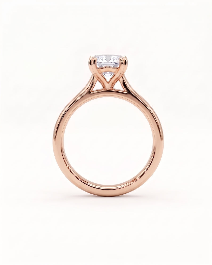 Emerald-cut diamond solitaire engagement ring set in a rose gold cathedral band.