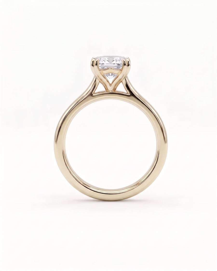 Emerald-cut diamond solitaire engagement ring set in a polished yellow gold cathedral band.