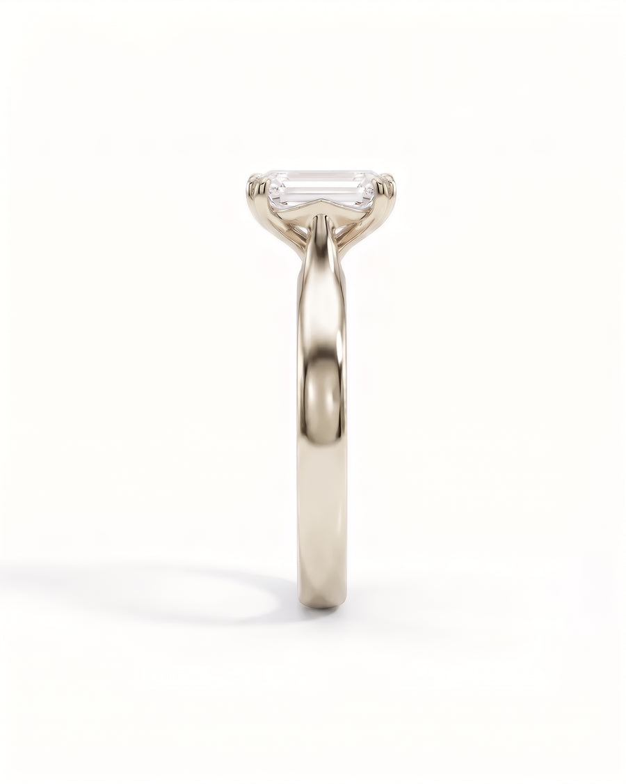 Emerald-cut diamond solitaire engagement ring with a cathedral setting in polished yellow gold.