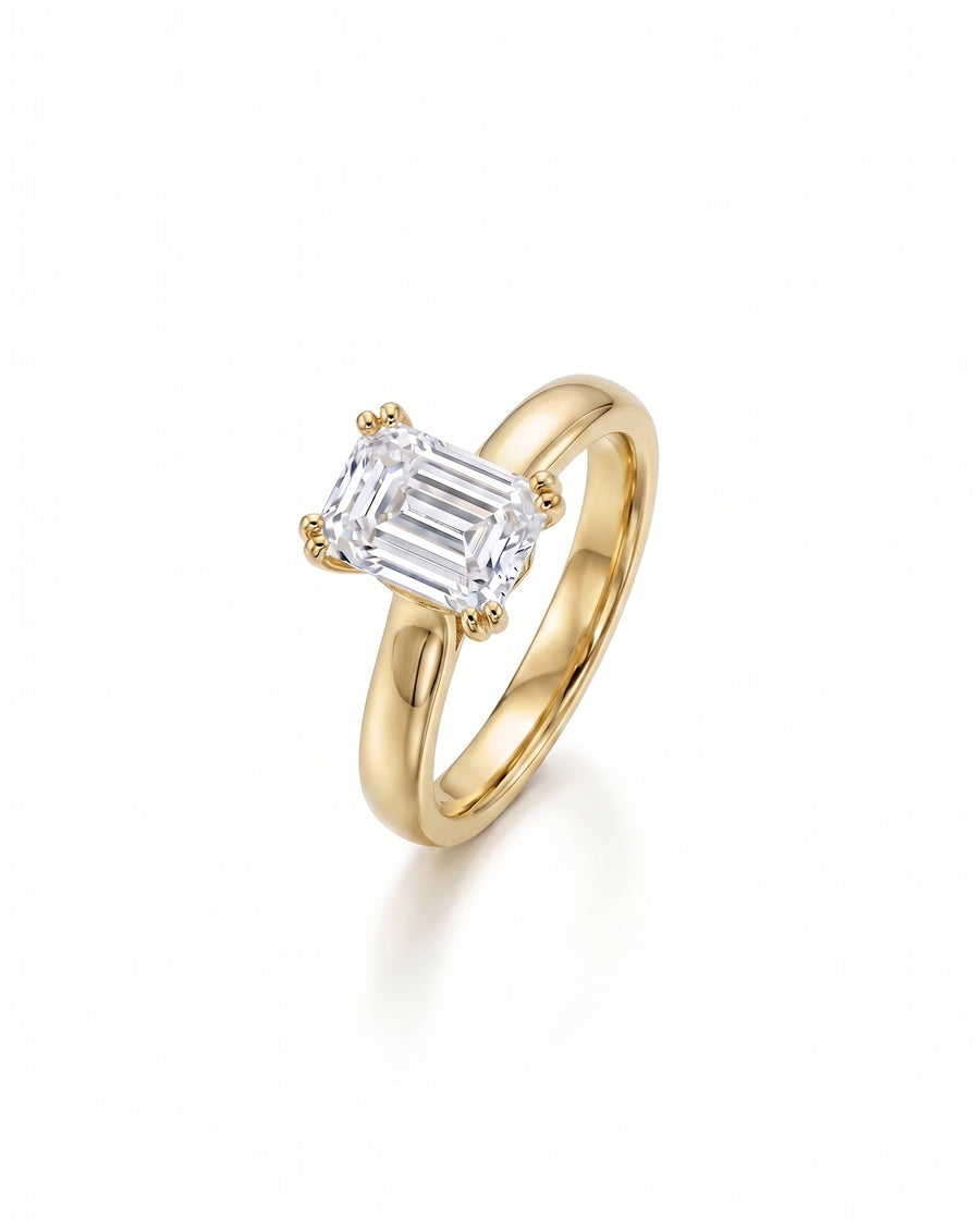 Yellow gold cathedral solitaire engagement ring with an emerald-cut diamond.