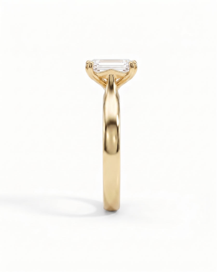 Yellow gold cathedral solitaire engagement ring with an emerald-cut diamond.