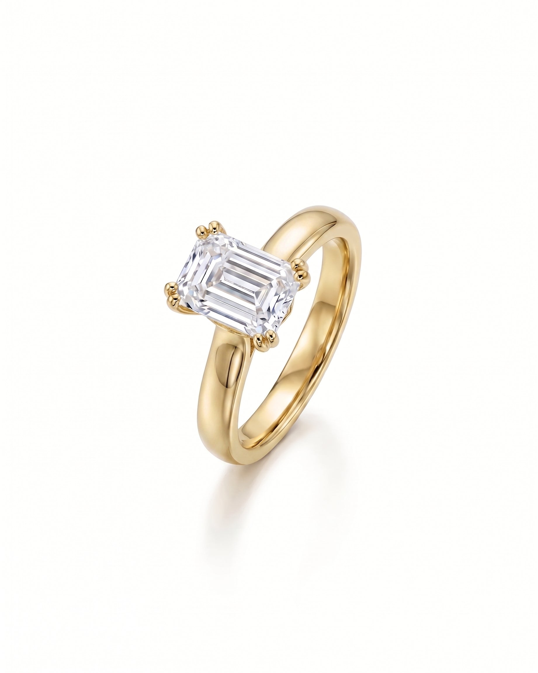 Yellow gold cathedral solitaire engagement ring with an emerald-cut diamond.