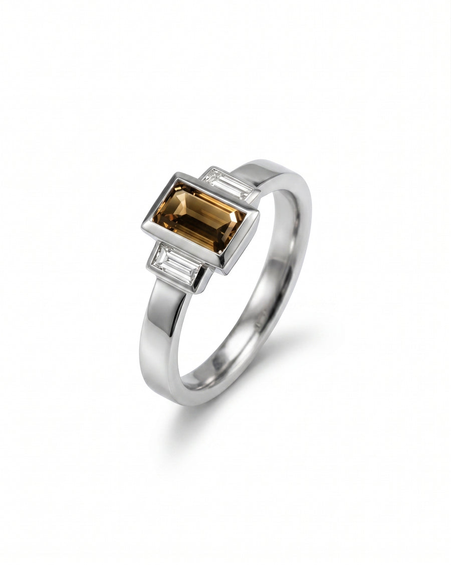 Silver ring with an emerald cut cognac diamond and two baguette side diamonds.