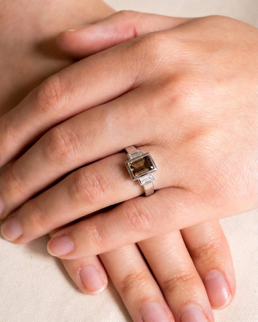 White gold ring with an emerald cut cognac diamond and baguette side stones.