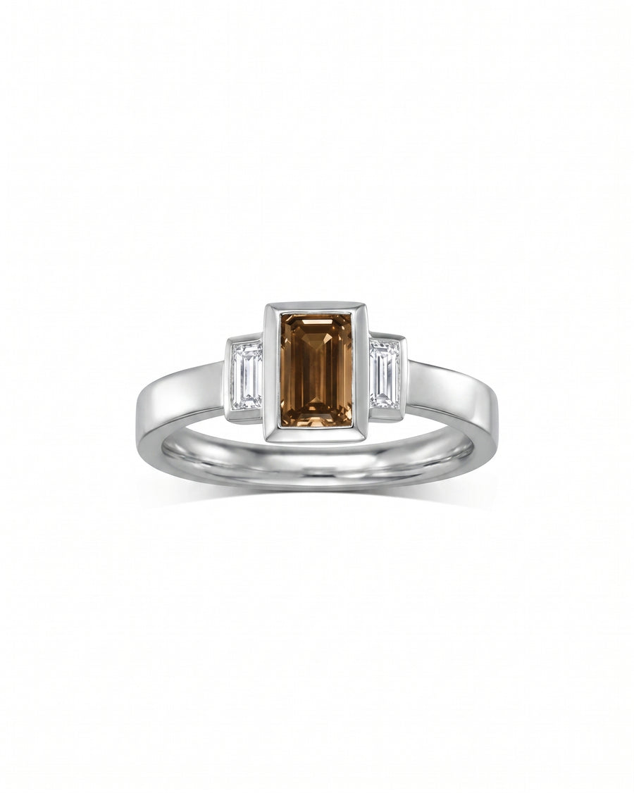 Silver ring with an emerald cut cognac diamond and two baguette diamonds.