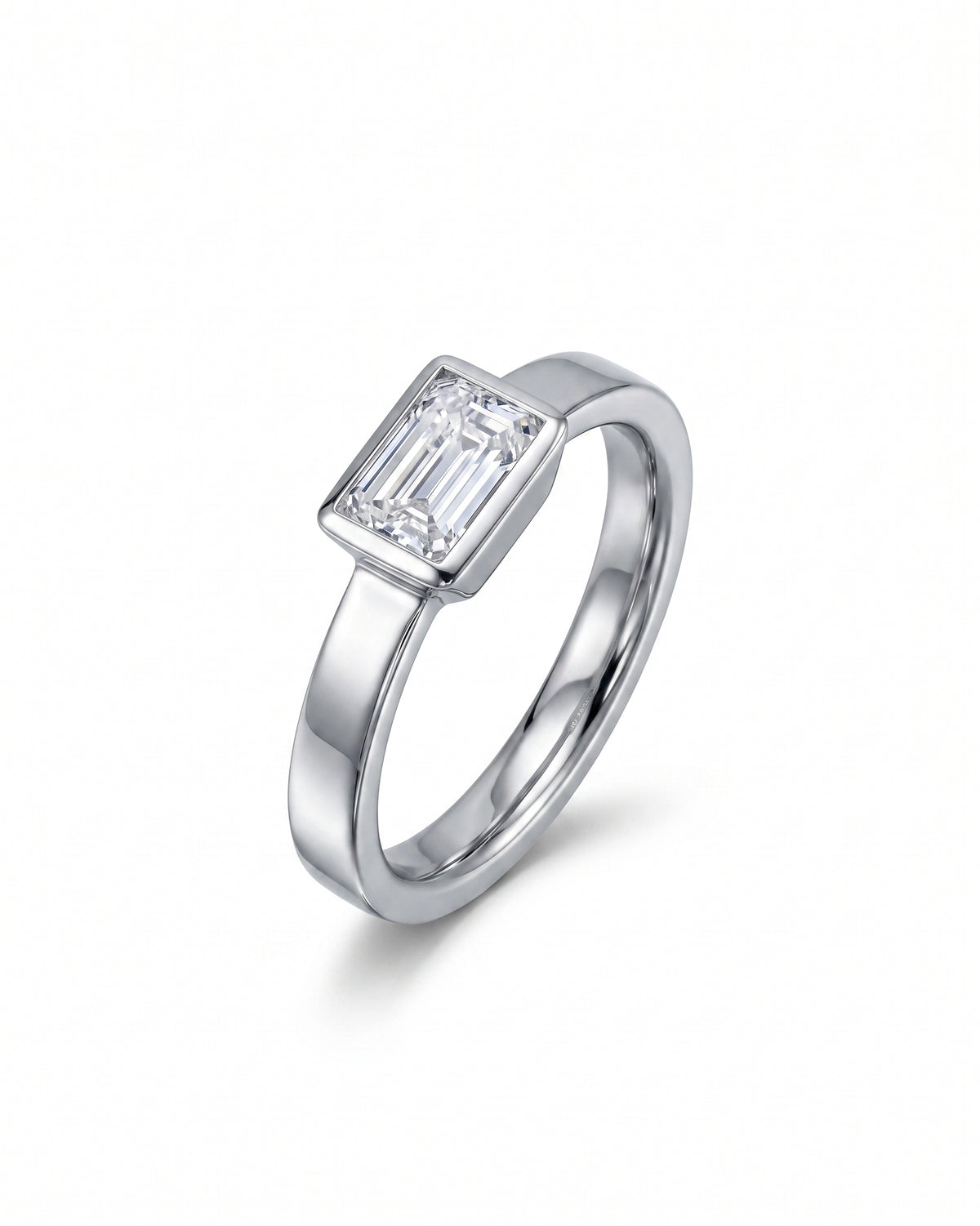 Emerald cut diamond set in a polished platinum bezel engagement ring.
