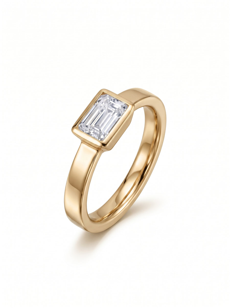 Emerald cut diamond engagement ring in a yellow gold bezel setting on a plain polished band.