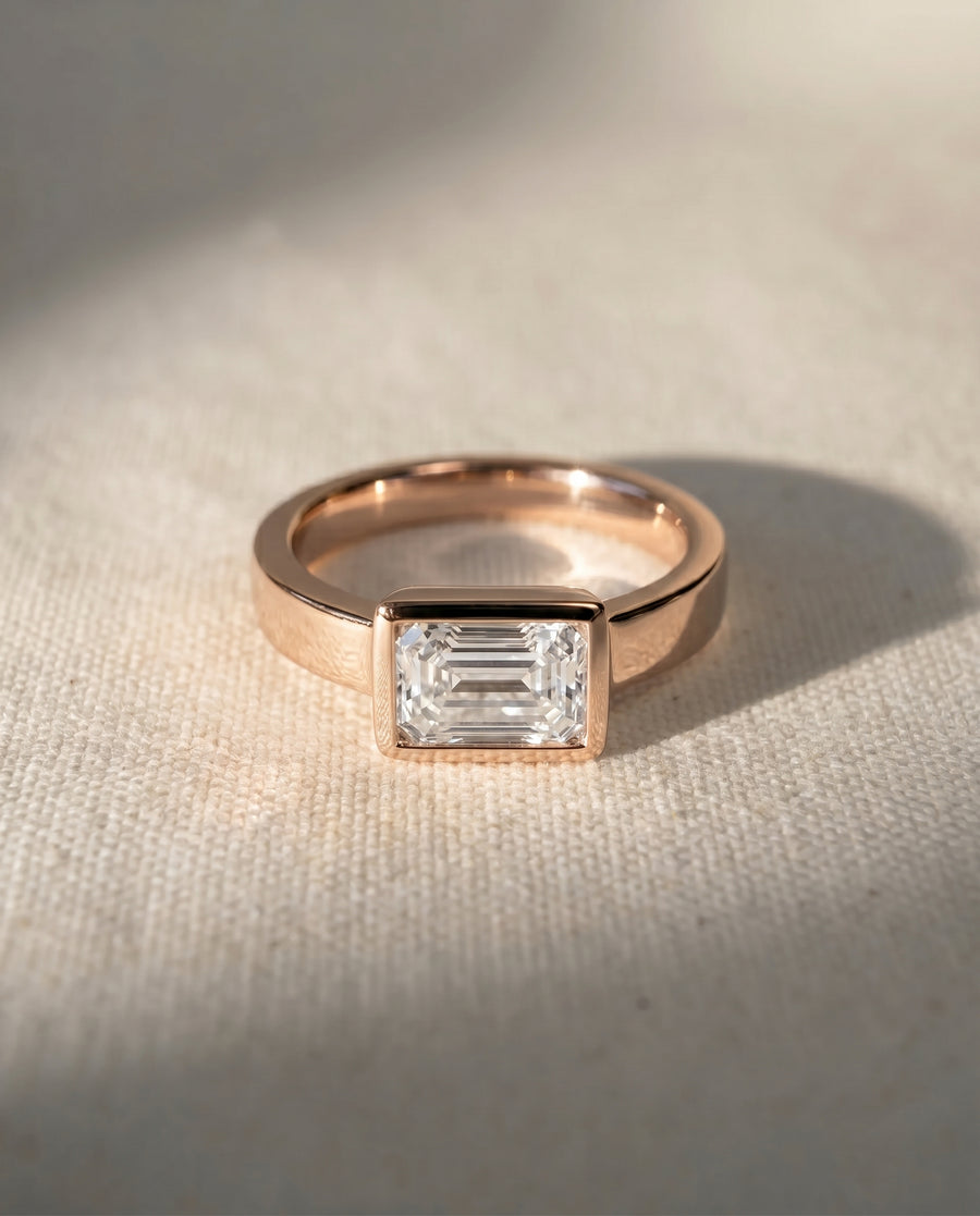 18ct rose gold engagement ring with an emerald cut diamond.