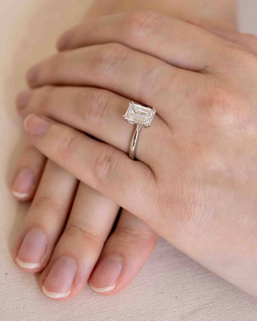 Silver engagement ring with an emerald cut diamond and hidden halo.