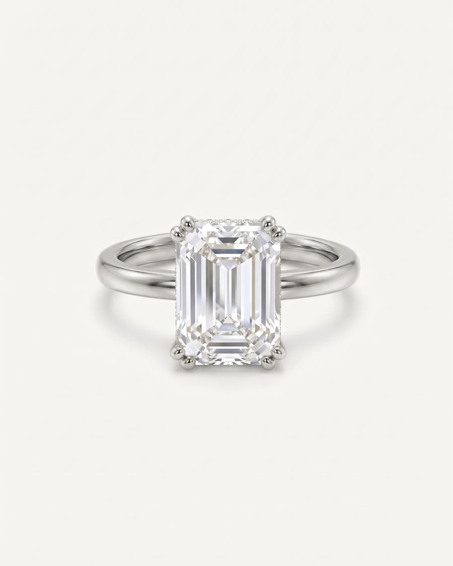 Emerald cut diamond engagement ring with a hidden halo set in a polished platinum band.