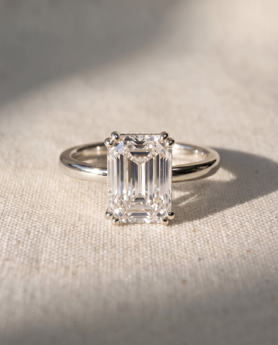 Emerald cut diamond engagement ring with a hidden halo set in a polished platinum band.