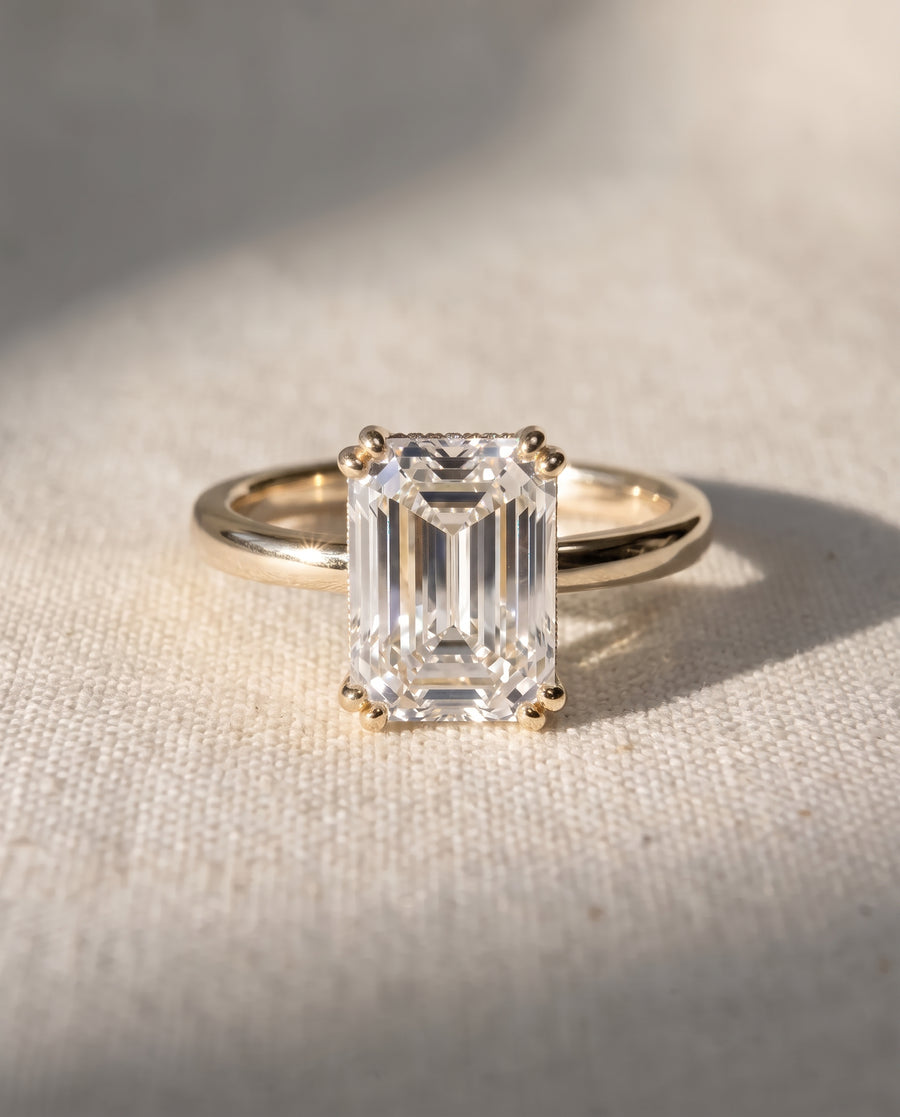 Emerald cut diamond engagement ring with a hidden halo set in a yellow gold band.