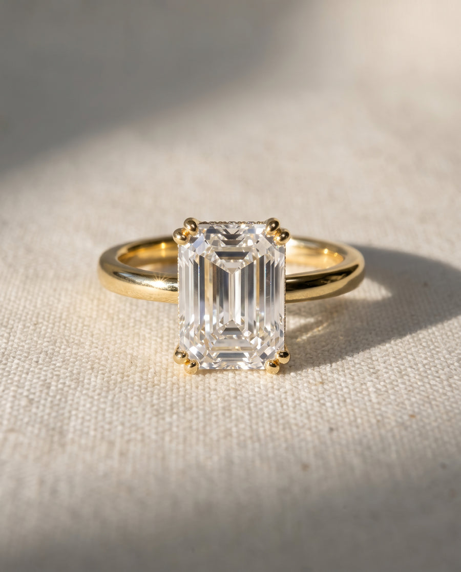 Emerald cut diamond engagement ring with a hidden halo set in a polished yellow gold band.
