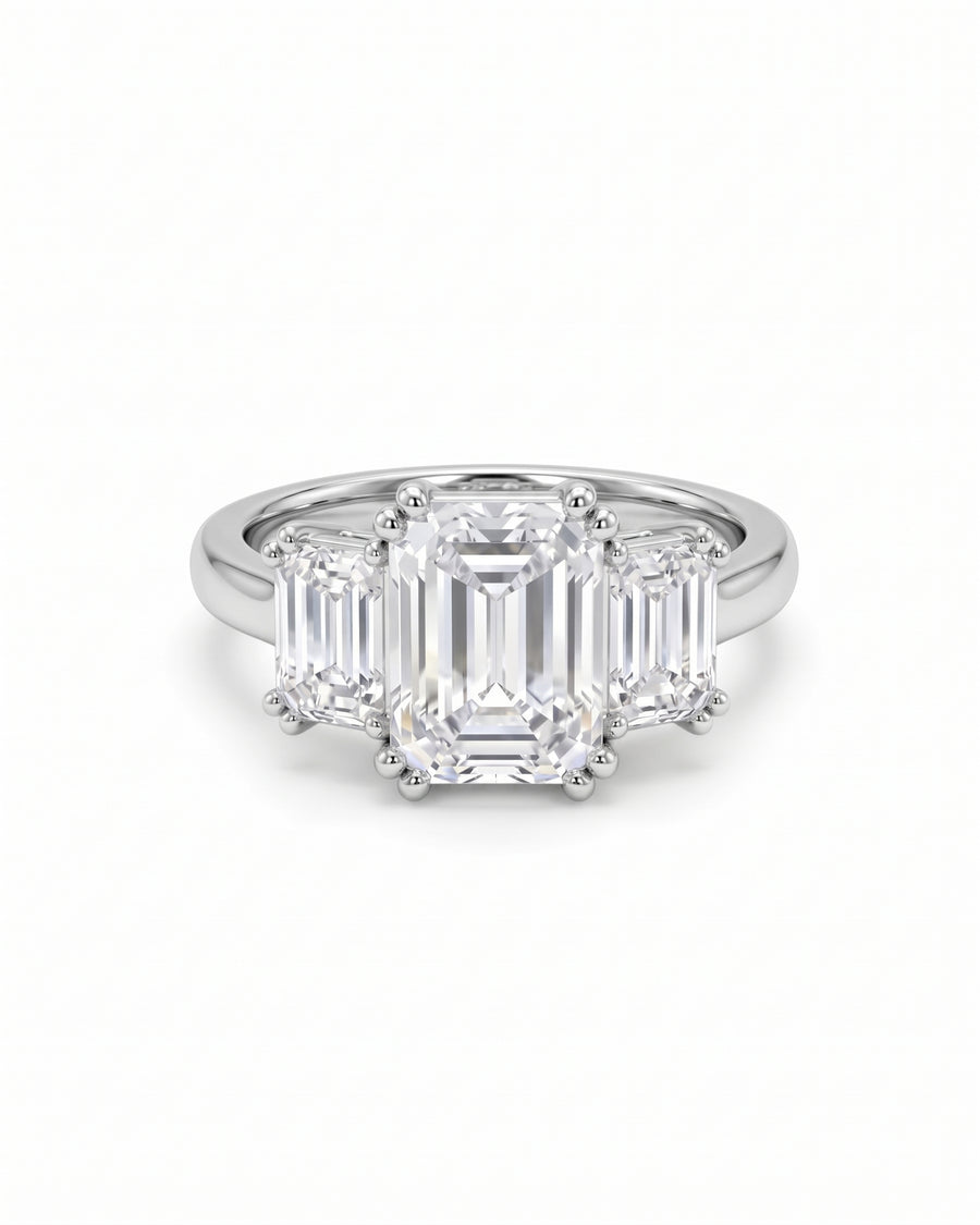 Platinum trilogy engagement ring featuring three emerald-cut diamonds on a polished band.