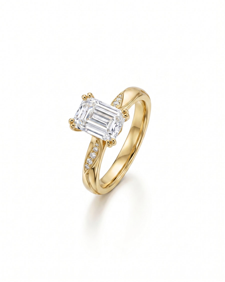 Gold engagement ring with an emerald cut diamond and pavé accents.
