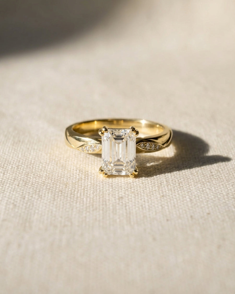 18ct yellow gold engagement ring with a 1ct lab-grown emerald cut diamond and pavé accents.