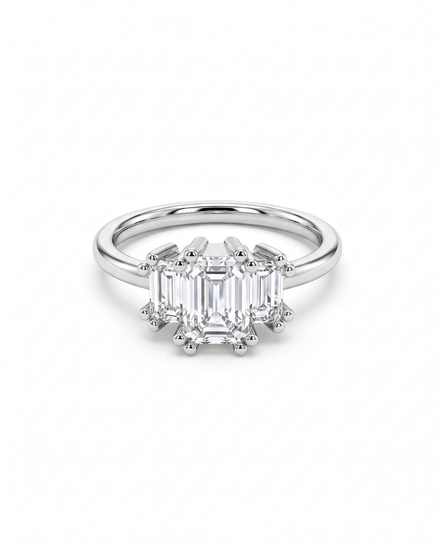 Three-stone engagement ring with emerald-cut diamonds set in polished white gold with claw prongs.
