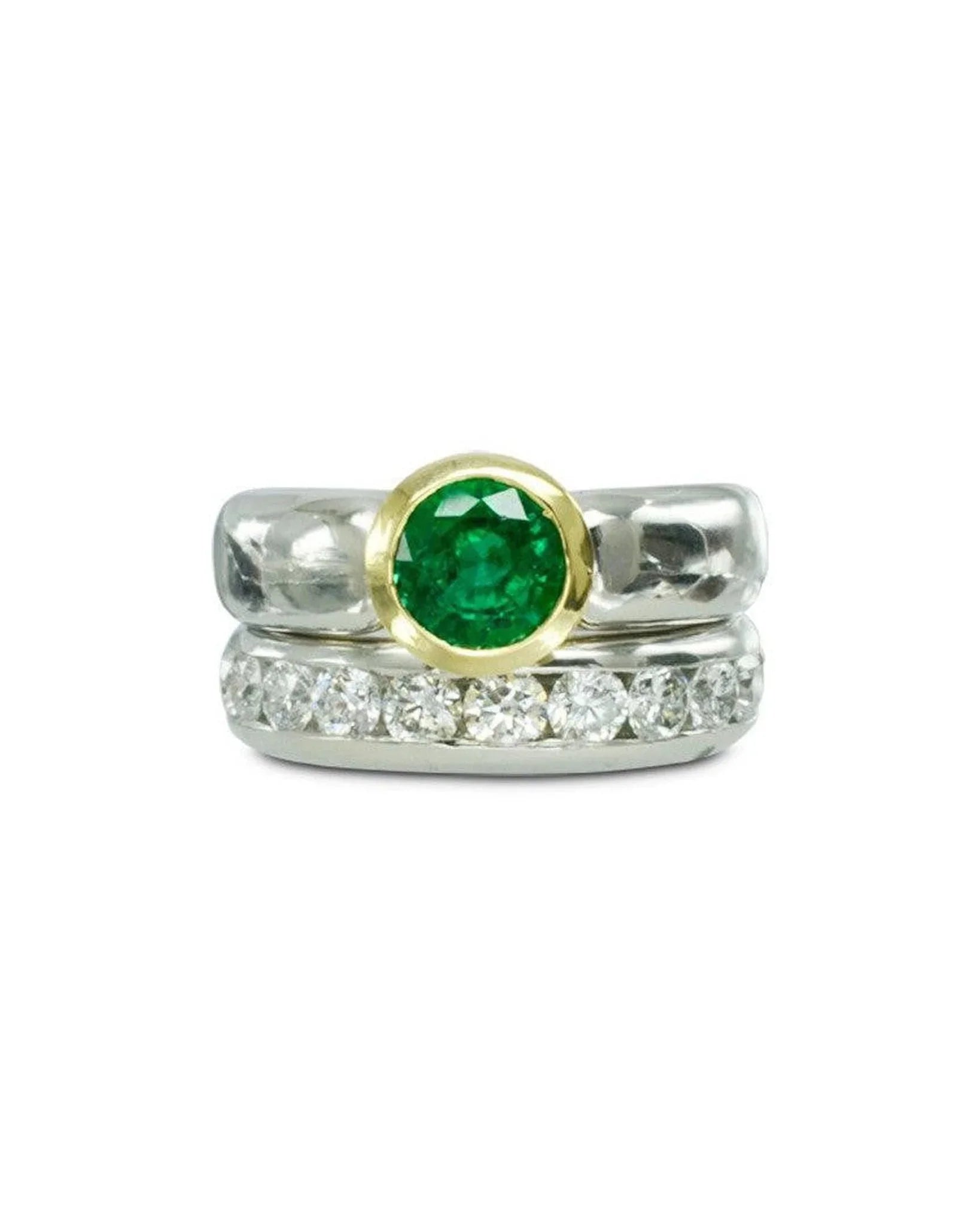 Two-tone engagement ring with round emerald center and diamond band on white background