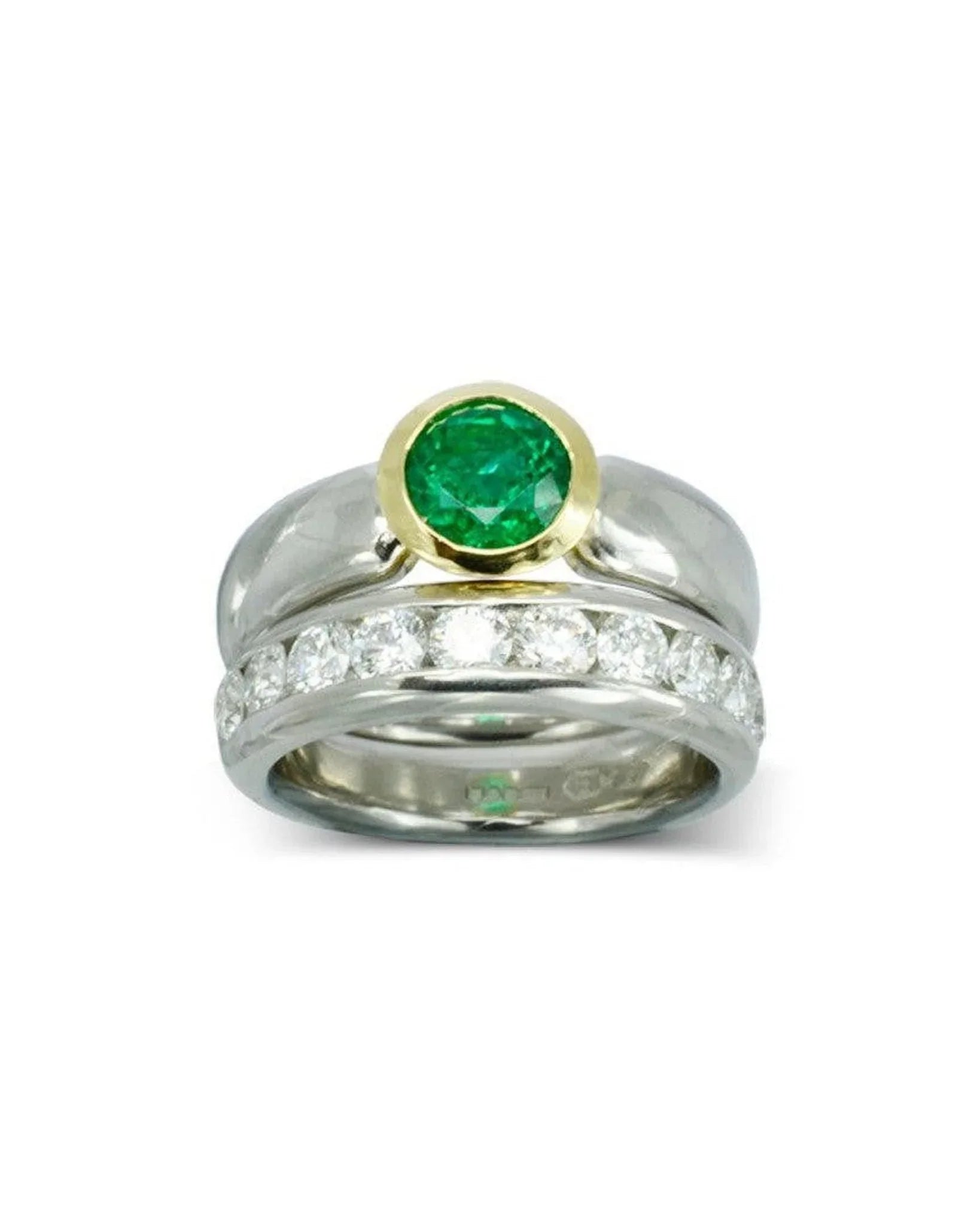 Two-tone engagement ring with a round emerald center and diamond band on white background