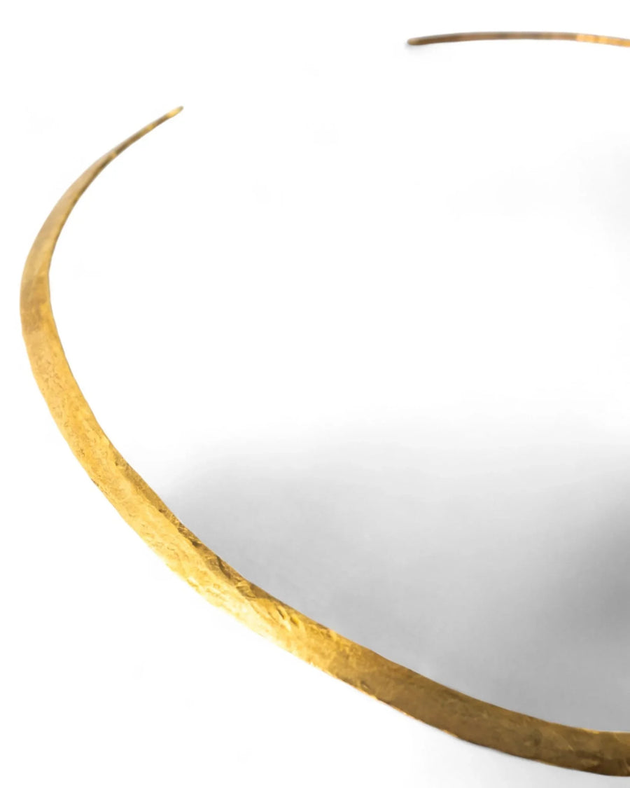 Handcrafted gold neck torc with textured, organic finish on a white background